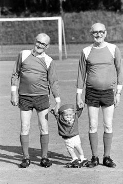 "Jubiläumsfußballturnier Sportplatz an der Bahnhofstraße": Zwei Herren im Fußballtrikot mit Kleinkind in Castrop-Rauxel, August 1977.