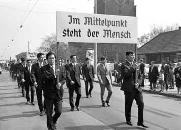 1. Mai-Kundgebung am "Tag der Arbeit", Castrop-Rauxel: Demonstrationszug auf dem Weg zum Marktplatz. Vermutlich koreanische Gastarbeiter tragen ein Gewerkschaftsplakat, 1960er Jahre.