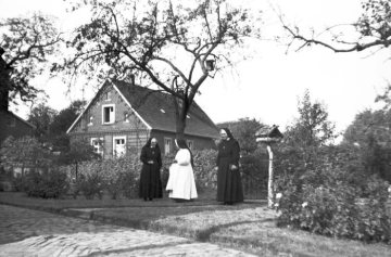 Alte Küsterei St. Pankratius in Rinkerode, 1963 - später Pfarrbücherei. Bildmitte: Clemensschwestern am Eingang des Krankenhausgartens gegenüber dem Krankenhaus, später Pfarrzentrum.