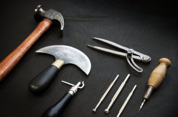 Werkzeuge des Sattlers: Hammer, Halbmondmesser, Rand- und Linienwerkzeug, Zirkel, Punziereisen und Ahle. Hofsattlerei Cosack, Arnsberg, Januar 2018.