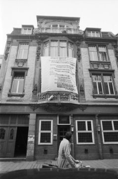 Das Gebäude in der Frauenstraße 24 in Münster im Jahr 1971; vor dem Erker im ersten Obergeschoß Transparent mit diversen Forderung, u.a. dieses Gebäude nicht abzubrechen, sondern zu sozialverträglichen Mieten instand zu setzten
