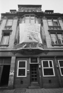 Das Gebäude in der Frauenstraße 24 in Münster im Jahr 1971; vor dem Erker im ersten Obergeschoß Transparent mit diversen Forderung, u.a. dieses Gebäude nicht abzubrechen, sondern zu sozialverträglichen Mieten instand zu setzten