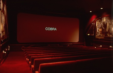 Cadillac Kino München. Kinosaal, es läuft der Film "Die City-Cobra" mit Sylvester Stallone in der Hauptrolle.