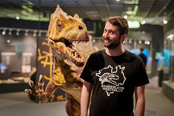 Moderator Fabian Nolte mit dem Modell eines Allosaurus im LWL-Naturkundemuseum in Münster
