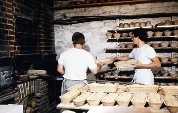 LWL-Freilichtmuseum Hagen, Museumsaktion in der Bäckerei: Bäcker beim Einschieben der geformten Brotlaiber in den Ofen