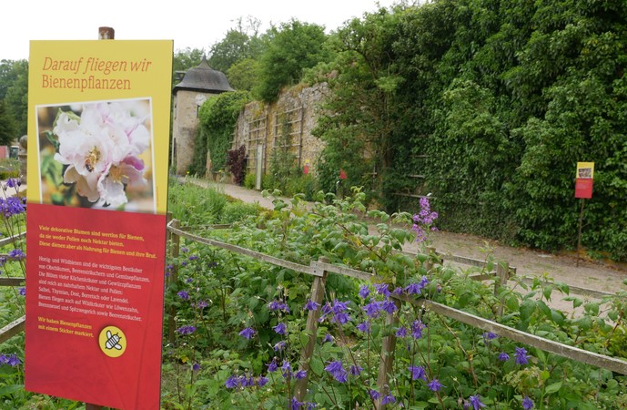 Ein rot-gelbes Schild aus der Gartenausstellung informiert über bienenfreundliche Pflanzen.