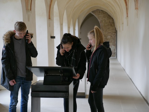 Drei Jugendliche hören sich den Audioguide in der Klausur an. Drei Jugendliche hören sich den Audioguide in der Klausur an.