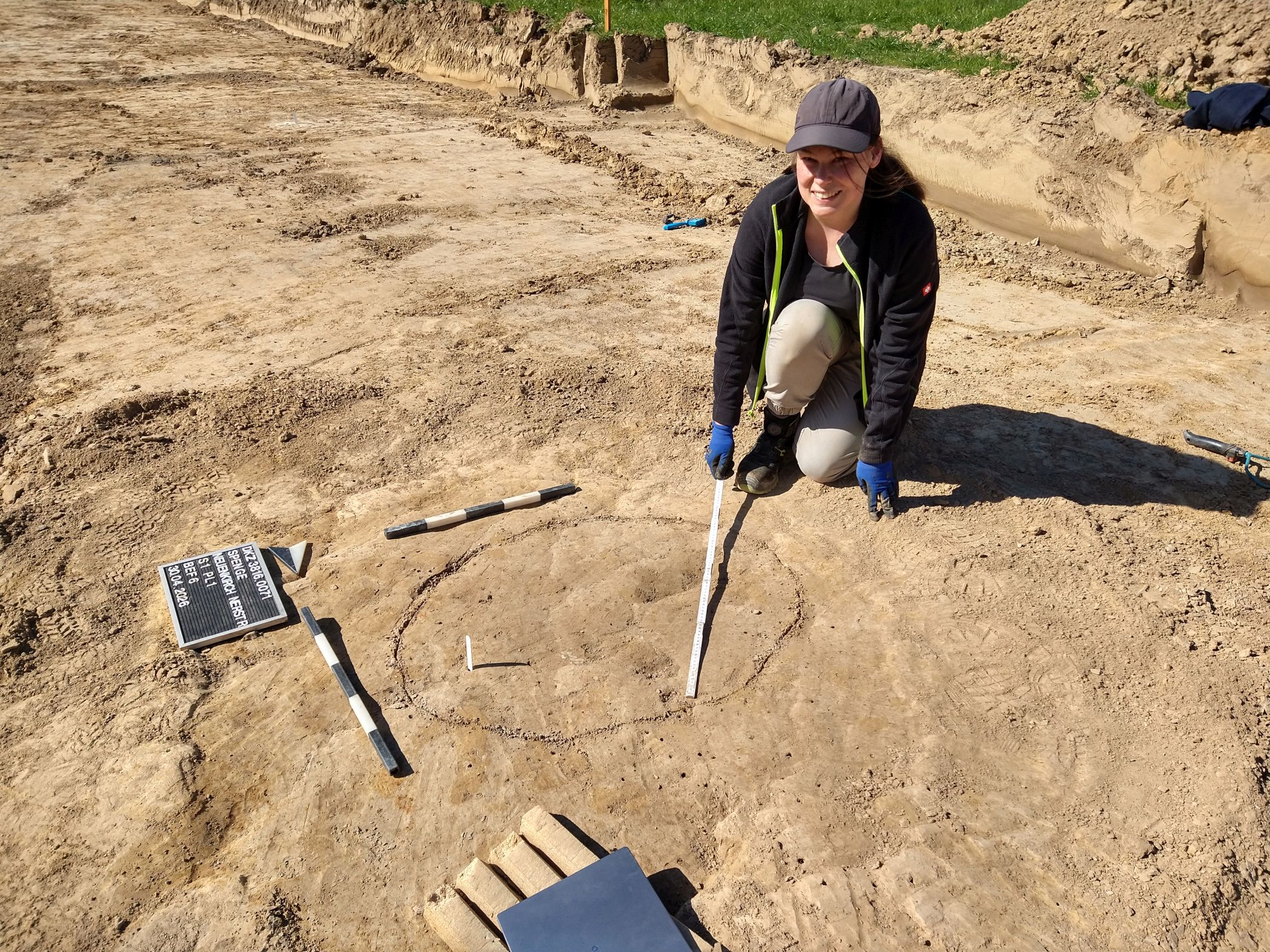 Archäologin Celine Bariszlovich beschreibt eine der Gruben, die sich nur schwach als Verfärbung abzeichnen. Jede Grube wird fotografiert und eingemessen<br>Foto: LWL/S. Spiong