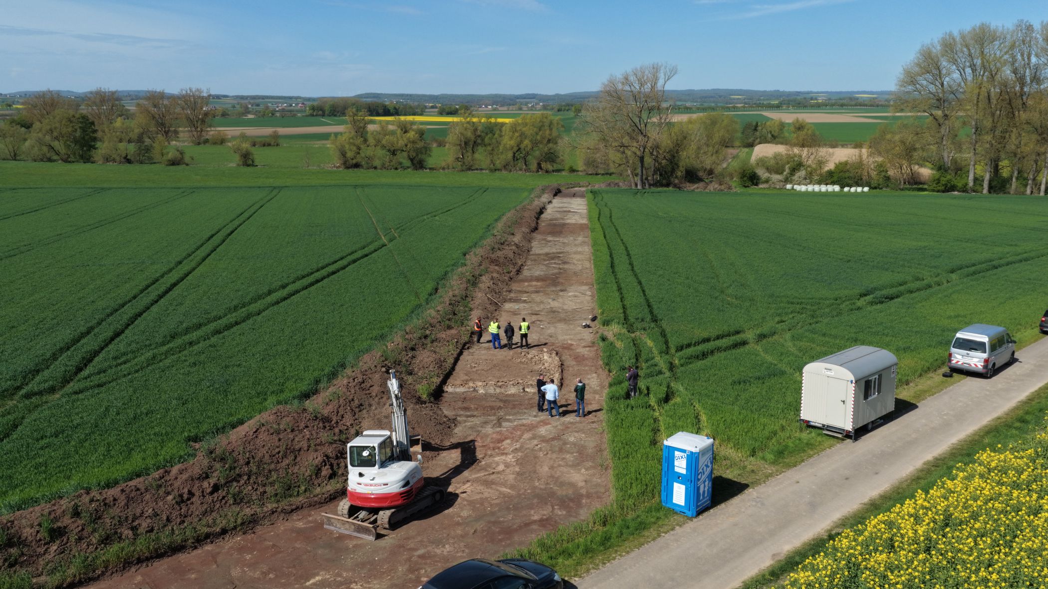Blick von Süden über die Grabung. Im Hintergrund entlang der Baumreihe fließt der Mühlenbach.<br>Foto: LWL-Archäologie/A. Koch