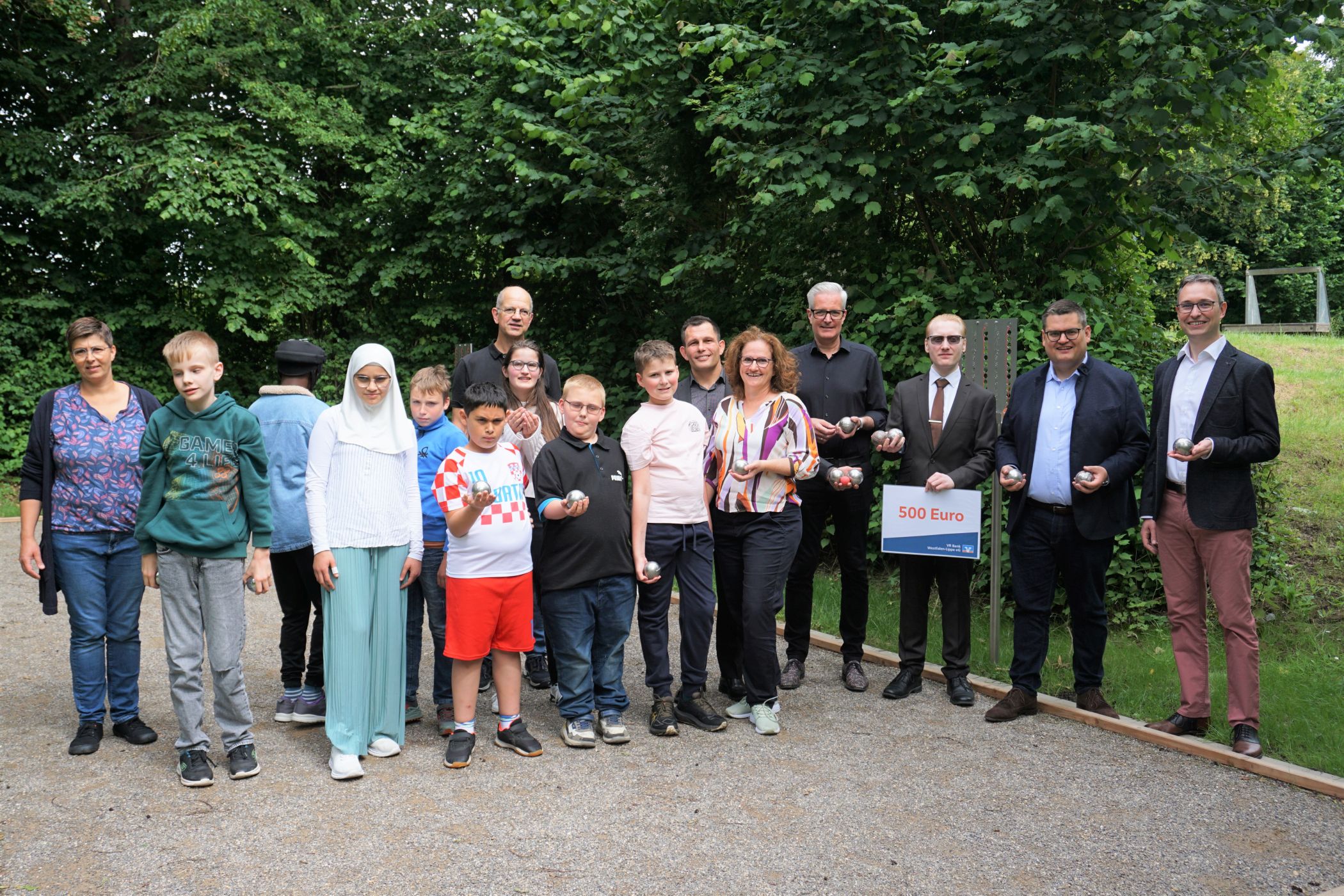 Benjamin Redeker (v.r./Leiter LWL-Regionalzentrum Schule und Bildung Soest), Urs Frigger (LWL-Bau- und Liegenschaftsdezernent), Jan Heinze (VR Bank Westfalen-Lippe), Andreas Liebald (Leiter von-Vincke Schule Soest), Dr. Silke Bachsleitner (Stellv. Schulleiterin von-Vincke-Schule), sowie Michael Zimmer und Achim Heinemann (beide Förderverein), sowie Schülerinnen und Schüler bei der Eröffnung der neuen Boule-Bahn.<br>Foto: LWL/Kim-Lea Uebach