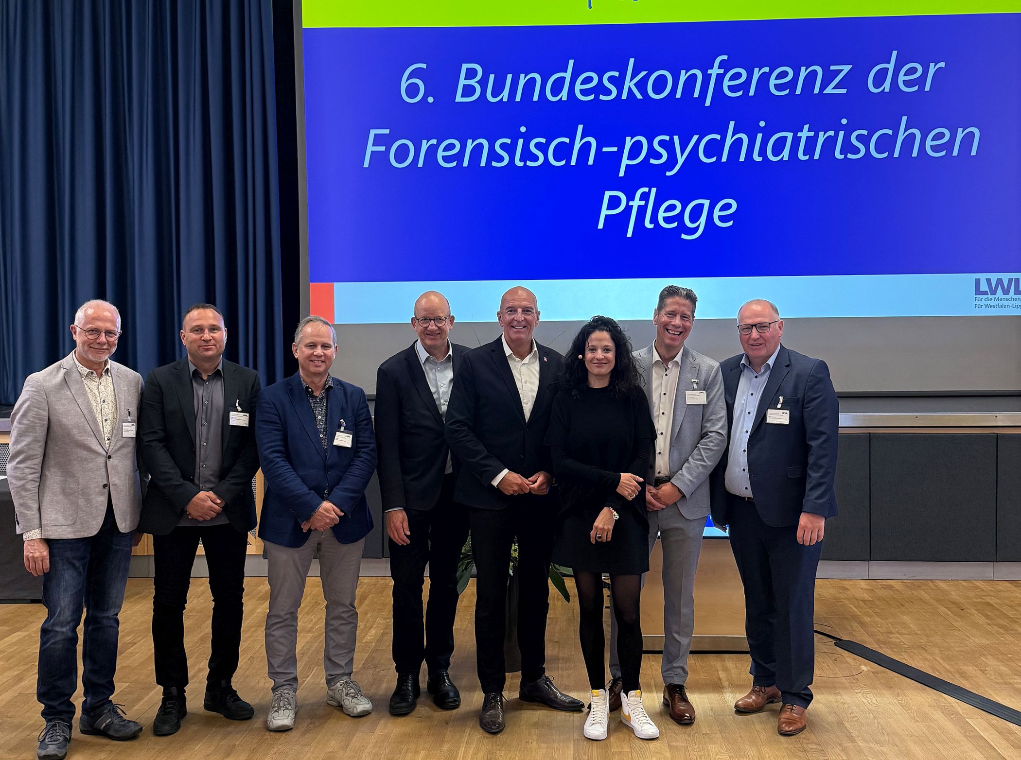 Bei der Bundeskonferenz der forensisch-psychiatrischen Pflege stellten Dr. Georg Lunemann (4.v.r.), Direktor des LWL, LWL-Maßregelvollzugsdezernent Tilmann Hollweg (4.v.l.) und die Pflegedirektoren der forensischen LWL-Kliniken (v.l.) Hubertus Gerlach, Sören Reinke, Axel Schröder, Stefan Schuchardt und Stephan Deimel die Pflege in den Mittelpunkt. Durch die Tagung führte Poetry Slammerin Dominique Macri.<br>Bild: LWL