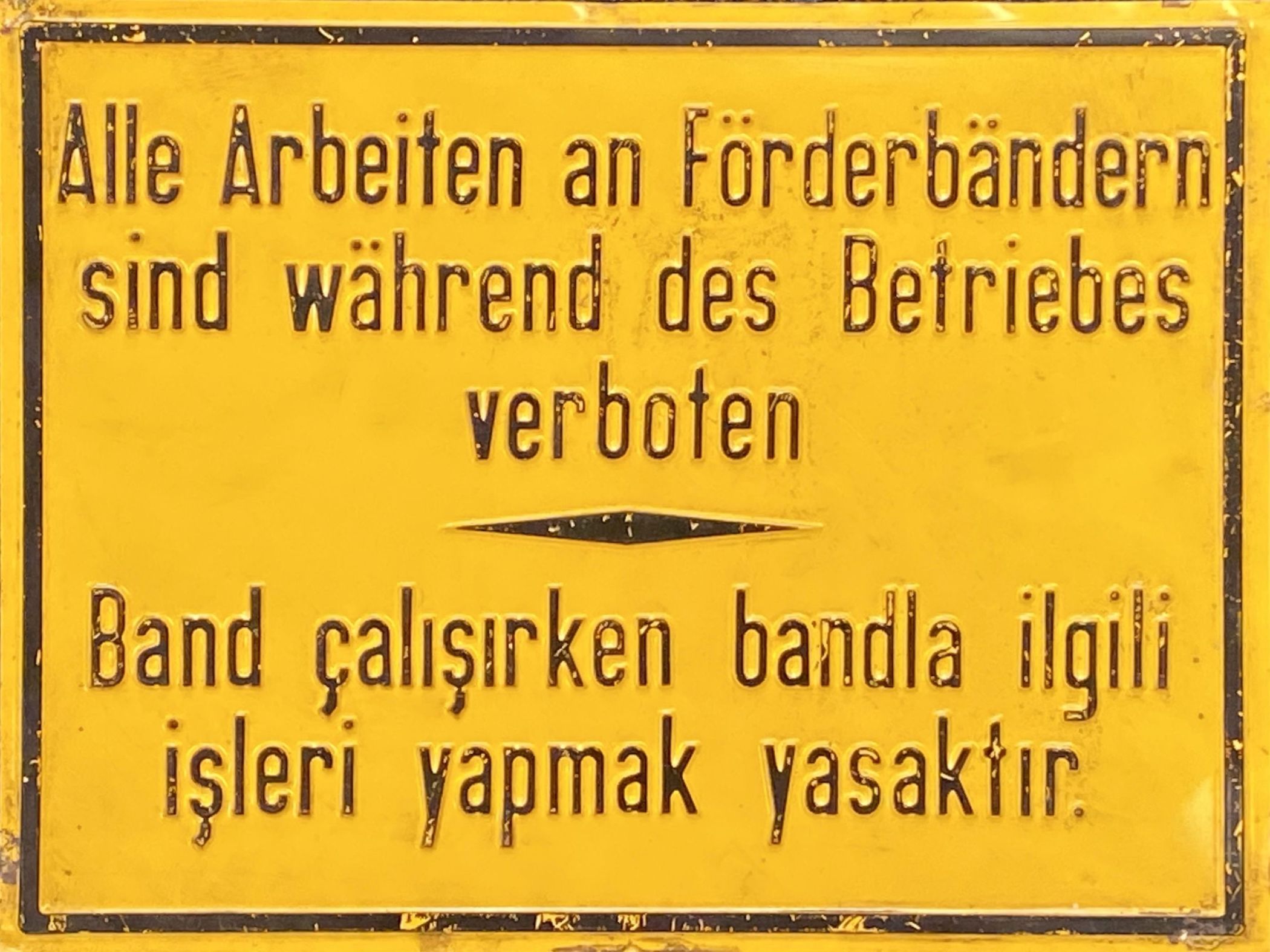 Zweisprachiges Warnschild von der Henrichshütte in Hattingen, das auf den Hüttenarbeiter und Betriebsrat Nuri DerviÅ�oÄ�lu (1938-2021) zurückgeht, undatiert. Leihgabe: LWL-Museum für Industriekultur, Dortmund.<br>Foto: LWL