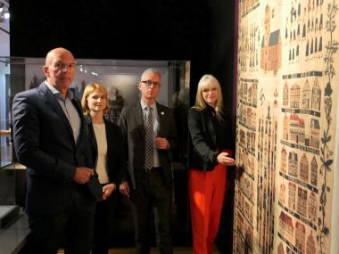 Der Direktor des Landschaftsverbandes Westfalen-Lippe (LWL) Dr. Georg Lunemann, Ausstellungskuratorin Carolin Mischer, Museumsdirektor Dr. Ingo Grabowsky und LWL-Kulturdezernentin Dr. Barbara Rüschoff-Parzinger (v.l.) präsentierten einen ersten Einblick in die Sonderausstellung &quot;. Der hier gezeigte Wandteppich von 1935 aus der Rotenburger Jakobikirche (Replik) verknüpft christliche und nationalsozialistische Motive.&lt;br&gt;Foto: LWL/Kristina Schellenberg 