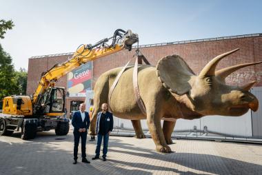 Der Direktor des LWL Dr. Georg Lunemann und Museumsdirektor Dr. Jan Ole Kriegs (von links) markieren den Startschuss am neuen Museumseingang mit dem Triceratops im Hintergrund.&lt;br&gt;Foto: LWL/Steinweg 
