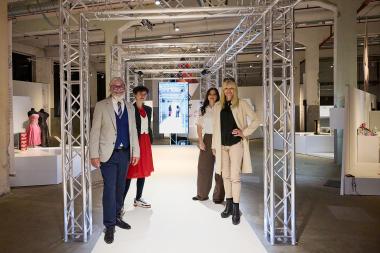 Martin Schmidt, Kommissarischer Museumsleiter, Sophie Hoelge und Jennifer Seeger, Kuratorinnen vom Textilwerk, sowie LWL-Kulturdezernentin Dr. Barbara Rüschoff-Parzinger (v.l.) auf dem Laufsteg. Auf dem Bildschirm im Hintergrund laufen zeitversetzt um einige Sekunden Videoaufnahmen der Besucherinnen und Besucher von ihrem Gang über den &quot;Catwalk&quot;.&lt;br&gt; Foto: LWL/Julia Gehrmann 