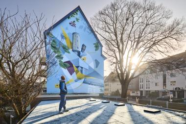 Im Jahr 2020 schuf Denis Kelle in Kooperation mit der Kreativagentur &quot;ArtKumpan&quot; ein Auftragskunstwerk für ein Architekturbüro - mit ikonischen Bielefelder Bauwerken und symbolischen Elementen wie der Paderborner Fahne als Ausdruck regionaler Identität.&lt;br&gt;Foto: LWL/Maxime P. Lindenbaum 
