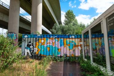 Container unter einer Brücke in Dortmund. Beim "Tag der offenen Box" dekorieren Profi-Sprayer einen Seecontainer auf dem Museumsgelände. Erwachsene und junge Besucher:innen können außerdem an einem Graffiti-Workshop teilnehmen.<br>Foto: LWL / Udo Kreikenbohm