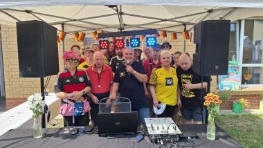 Mit Freude dabei: Mitarbeitende, Bewohnerinnen und Bewohner sowie DJ "Atommic" (Mitte) feierten ein Sommerfest im Garten des LWL-Pflegezentrums Dortmund unter dem Motto "Fußball".<br>Foto: LWL / Philipp Stenger