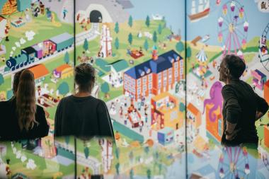 Besuchende vor einem überdimensionalen Wimmelbild zum Thema Essen.<br>Foto: LWL/ Malte Hömbach