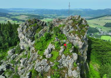 Blick von Südosten auf den Feldstein. Die Fundstelle ist beim roten Punkt. <br>Foto: LWL-Archäologie für Westfalen/F. Geldsetzer