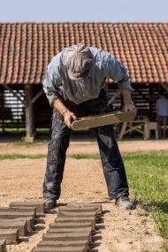 Museumsmitarbeiter Sebastian Henjes demonstriert die Trocknung der Ziegelrohlinge auf langen Sandbahnen, wie sie damals üblich war.<br>Bild: LWL / Philipp Harms