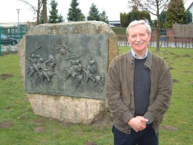Dieter Grabenmeier am Ort seiner ersten Ausgrabung in Beckum, wo eine Tafel an die Entdeckung des berühmten Fürstengrabens erinnert. <br>Foto: LWL</br>