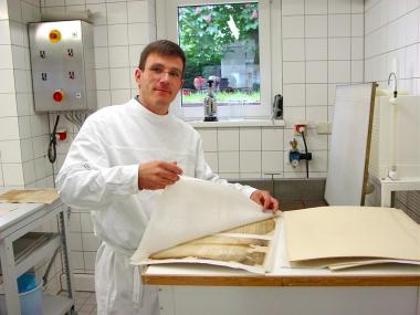 In der Restaurierungswerkstatt des LWL-Archivamtes: 'Anfasern' heißt das Verfahren, mit dem Restaurator Winfried Feuerstein die Löcher in einer alten Urkunde schließen kann.		<br>Foto: LWL</br>