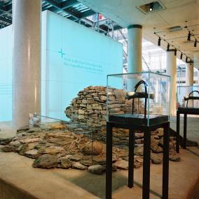 In Höxter-Albaxen bestatteten die Hinterbliebenen vor fast 4000 Jahren ihren Angehörigen unter einem steinernen Grabhügel. Im Hintergrund einer der farblich schimmernden Würfel, in denen die Archäologen im neuen Museum in Herne besondere Themen inszenieren. <br>Foto: LWL/Brentführer</br>