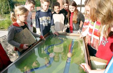 Im Emsgarten probiert die Klasse 7 c der Gesamtschule Saer-beck am Modell aus, wie sich der Wasserabfluss in einem begradigten und in einem gewundenen Flussabschnitt verhält.&lt;br&gt;Foto: LWL/Egbert&lt;/br&gt; 