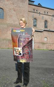 Museumsmitarbeiterin Andrea Hubert mit dem Plakat der Filmschauplätze NRW. <br>Foto: WIM<br />