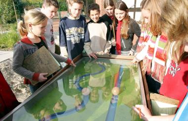 Schüler der Maximilian-Kolbe-Gesamtschule/Saerbeck untersuchen die Abhängigkeit der Fließgeschwindigkeit des Wassers vom Verlauf des Flussbettes an einem der Funktions-modelle im Emsgarten des LWL-Museums. <br>Foto: LWL/Egbert<br />