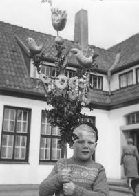 Mit Buchsbaum, Süßigkeiten, einem Apfel und Gebäck in Vogelform ist der Palmstock dieses Jungen aus Anholt (Kreis Borken) im Jahre 1957 prächtig geschmückt. <br>Foto: LWL-Archiv/Schlechtriem<br />