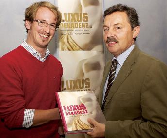 LWL-Museumsleiter Dr. Rudolf Asskamp (r.) begrüßt Michael Postel als 10.000 Besucher der Ausstellung ¿Luxus und Dekadenz¿ mit einem Ausstellungskatalog. <br>Foto: LWL<br />