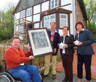 Vor dem Haus Uhlmann aus Ovenhausen übergeben Franz Voß (2.v.l.), Martina Bömelburg  (3.v.l.) und Wilhelmine Klatt (beide geb. Voß) ein Wandbild und ein Teeservice aus dem früheren Besitz der jüdischen Familie Uhlmann an Dr. Heinrich Stiewe  (l.) vom LWL-Freilichtmuseum. 	Foto: LWL/Jähne