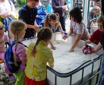 Kinder beim Wühlen im Zellstoffbrei. Wer eines der bunten Plastikkugel in dem Zellstoffbrei findet,  bekommt einen Preis. <br>Foto: LWL/Köhler<br />