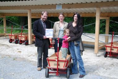 Gemeinsam mit LWL-Museumsleiter Dr. Jan Carstensen (li.) nahm Maren Lampe, die Vorsitzende der Freunde des LWL-Freilichmuseums Detmold e.V. (m), die neuen Wagen in Augenschein. Die kleine Anna Niemeier und ihre Mutter weihten den ersten Bollerwagen ein. <br>Foto: LWL<br />