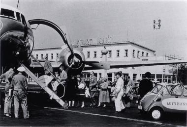 Lufthansa-Passagiere um 1960 am Frankfurter Flughafen auf dem Weg in den Urlaub. Rechts im Bild eine ¿Lufthansa-Knutschkugel¿ (BMW Isetta).<br>Foto: Privatbesitz<br />