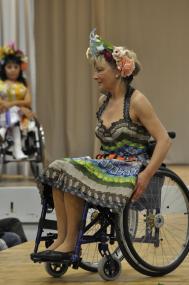 Ein Rollstuhl-Model präsentiert ein zweiteiliges Regenbogenkleid, gefertigt aus Etiketten.<br>Foto: Pia Fischer, Berlin<br />