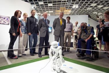 LWL-Direktor Dr. Wolfgang Kirsch (Bildmitte) zeigt sich beeindruckt vom tanzenden, humanoiden Roboter Nao. <br>Foto:LWL/Oblonczyk<br />