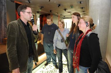 Dank eines Funkmikros und der Kopfhörer mit Funkempfänger kann der Museumspädagoge in moderater Lautstärke durch die Ausstellung führen. <br>Foto: LWL/W. Quickels<br />