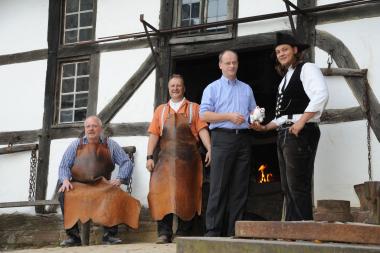 Die beiden Schmiede des LWL-Freilichtmuseums Detmold Werner Gerke und Wolfgang Göhmann freuen sich, dass Heiner Marx dem Wandergesellen Alexander Polonis (v. l.) symbolisch ein Sparschwein überreicht. <br>Foto: LWL/Klein<br />
