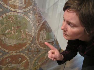 Fantasievoll und lebendig: Kunsthistorikerin Sina Schröder zeigt, welche Geschichten dieser Chormantel aus dem 13. Jahrhundert ¿ eine Leihgabe des Benediktinerstifts St. Paul im Lavanttal ¿ erzählt. In dieser Szene verteidigen zwei Raben den Leichnam des Hl. Blasius gegen wilde Tiere. <br>Foto: LWL/Maria Tillmann<br />