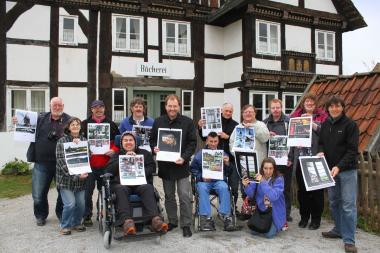 Die Gruppe der Lebenshilfe Detmold präsentiert gemeinsam mit LWL-Museumsleiter Dr. Jan Carstensen (vorne, Mitte) ihren im LWL-Freilichtmuseum Detmold entstandenen Fotokalender vor dem Lieblingsmotiv, der Bäckerei im ¿Paderborner Dorf¿. <br>Foto: LWL/Jähne<br />