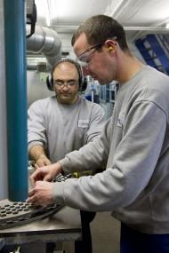 Sascha Thiele stellt die Federn in den Teller der Schleifmaschine. <br>Foto: LWL/Arendt<br />