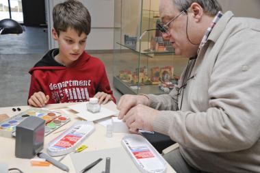 Dieter Matysik erklärt einem jungen Besucher im Schiffshebewerk das Hobby des Kartonmodellbaus.<br> Foto: LWL <br />