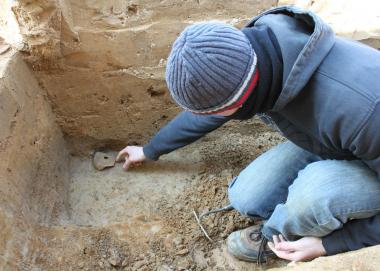 Der Bochumer Student Jona Schröder bei der Bergung des Tintenfässchens im Grabungsprofil. <br>Foto: LWL/Tremmel