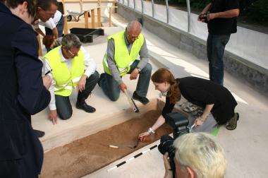 GrabungsCAMP mit Fundgarantie: LWL-Direktor Dr. Wolfgang Kirsch (Mitte) legt mit Hilfe von Karoline Frede, Mitarbeiterin der Museumspädagogik, und unter fachmännisches Aufsicht von Prof. Dr. Michael Rind (links), westfälischer Chefarchäologe, und Museumsleiter Dr. Josef Mühlenbrock (zweiter von links) ein frühmittelalterliches Kurzschwert frei.<br>Foto: LWL/Kalla