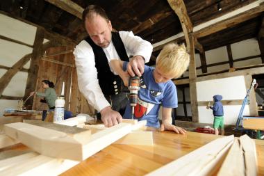 Gebäuderestaurator Timm Miersch zeigt Kevin, wie das Gestell für die Wassermühle gebaut wird. <br>Foto: LWL/Klein