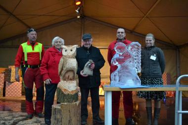 Herr Daubel (Mitte) hat die Eule und den Engel für einen guten Zweck ersteigert. Daneben Holzbildhauer Werner Korzen (l.), Irmgard Eberhard (2.v.l.) vom Förderverein, Künstler Joachim Knorra (2.v.r.) und Jasmin Soyak (r.), Organisatorin des Weihnachtsmarktes.<br>Foto: LWL