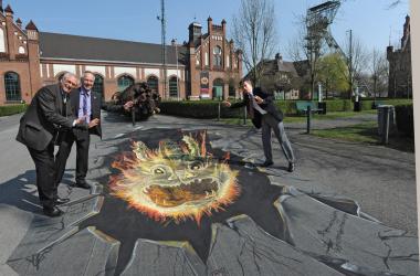 Dr. Wolfgang Kirsch, Dirk Zache und Dr. Eckhard Schinkel (v.l.) im Ehrenhof der Zeche Zollern, wo der Feuerleviathan als Straßengemälde auf die Ausstellung aufmerksam macht. <br>Foto: LWL/Appelhans